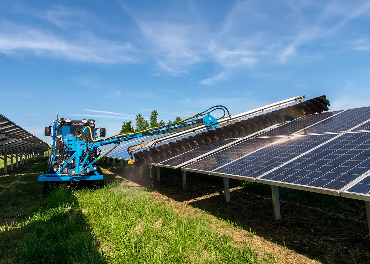 Eine große Freiflächen-Photovoltaikanlage / Solarpark wird professionell mit einer speziellen Bürstentechnik gereinigt, um Schmutz effektiv zu entfernen und den Ertrag zu steigern